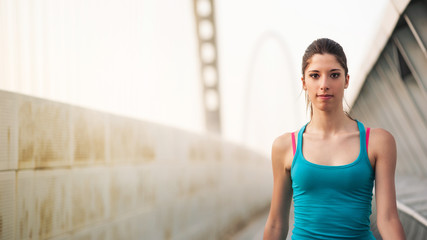 Fototapeta na wymiar Young woman running outdoors on a modern bridge. Workout wellnes