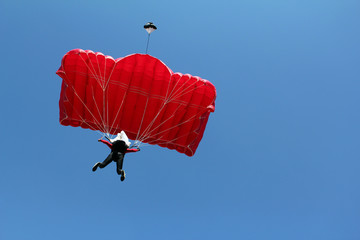 parachutist with red parachute on blue sky