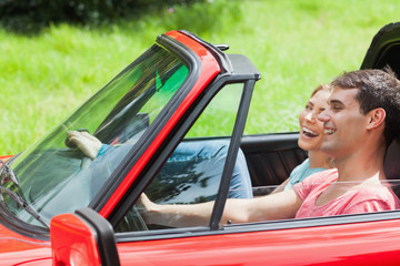Smiling young couple having a ride in red cabriolet