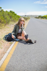 Pensive blonde woman sitting on the roadside
