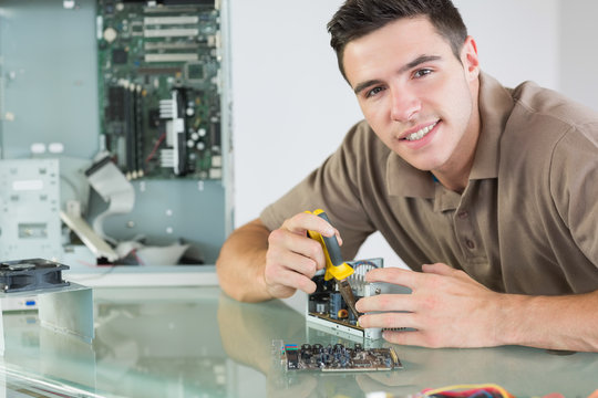 Handsome smiling computer engineer repairing hardware with plier