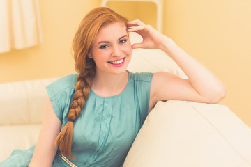 Happy redhead sitting on the couch looking at camera