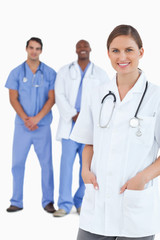 Fototapeta premium Smiling female doctor with male colleagues behind her