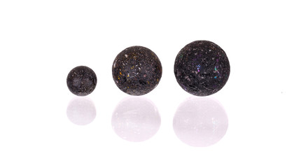 Assorted black glass marbles arranged over a white background