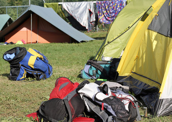 backpacks of hikers in the midst of camping tents