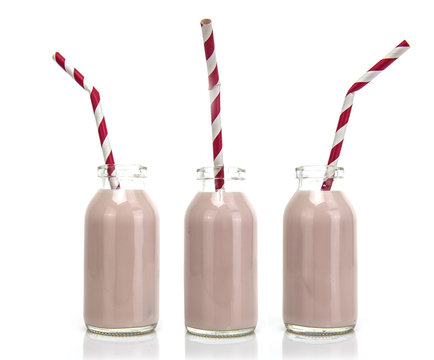 Three Bottles of pink milk with red and white striped straws