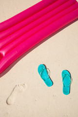 Fototapeta premium green flip-flops meet red air mattress