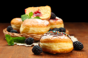 Tasty donuts with chocolate and berries on wooden table