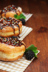 Tasty donuts with chocolate and berries on wooden table