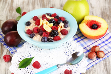 Oatmeal in plate with berries on napkins on wooden table