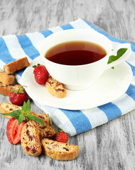 Cup of tea with cookies and strawberries on table close-up