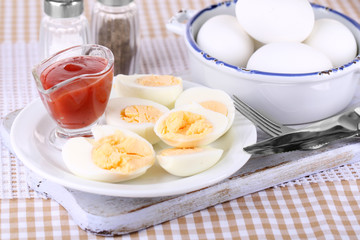 Boiled eggs on wooden board on tablecloth