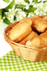Tasty croissants in wicker basket on table on white background