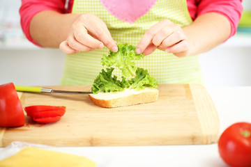 Happy smiling woman in kitchen preparing  sandwich, close up