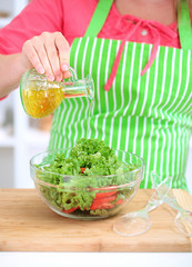 Happy smiling woman in kitchen preparing vegetable salad