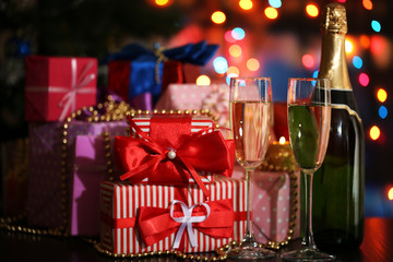 Many gifts and glasses of champagne on bright background