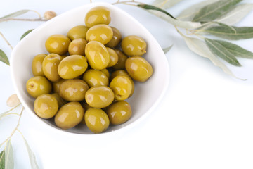 Olives in bowl with branch isolated on white