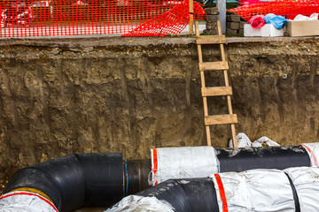 Wooden ladder in a fresh trench, layers of soil.