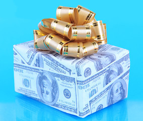 Gift box with bow covered dollars on blue background