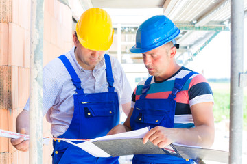 Handwerker kontrollieren Pläne auf einer Baustelle