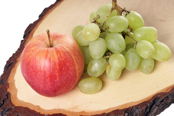Weintrauben und Apfel auf einem Holzbrett