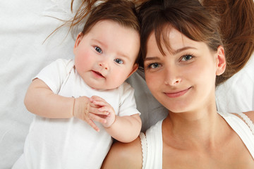 happy young mother with cute baby lying in bed