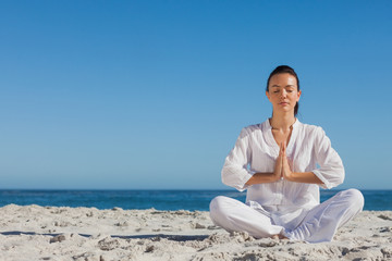 Naklejka na ściany i meble Peaceful woman practicing yoga on the beach