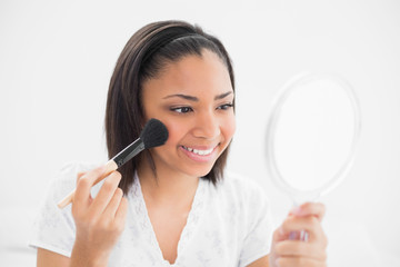 Joyful young dark haired model applying powder on her face