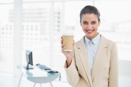 Content smart brown haired businesswoman holding a cup of coffee