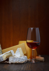 Red wine and cheese assortment on wooden table