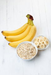 Bowl of oat flakes with sliced banana on wooden table