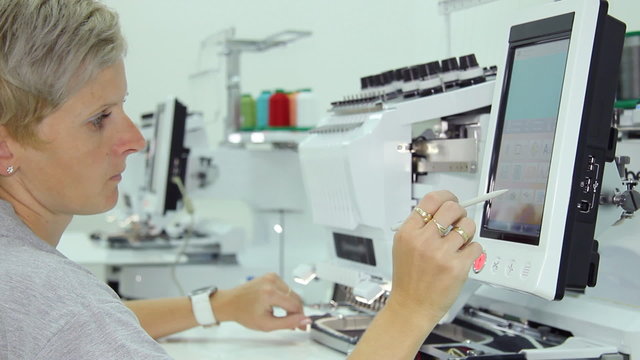 Woman working on computerized machine embroidery