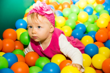 Fototapeta na wymiar Happy child girl in colored ball on playground