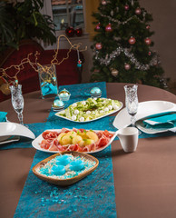Holiday-decorated table, Christmas tree, ham and melone, and sal