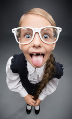 Fototapeta na wymiar Wide angle portrait of little girl in glasses tongue gesturing