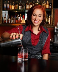 Beautiful redhead barmaid making cocktail