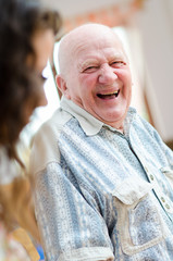 Happy senior man sitting indoor and laughting