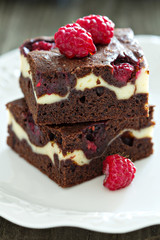 Cheesecake brownies with raspberry stacked on a plate