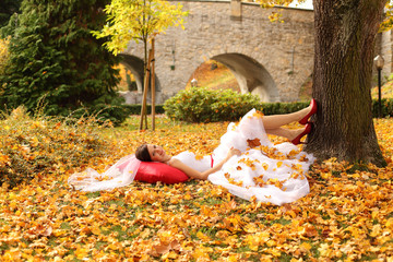 Piękna panna młoda w jesiennych kolorowych liściach. - obrazy, fototapety, plakaty