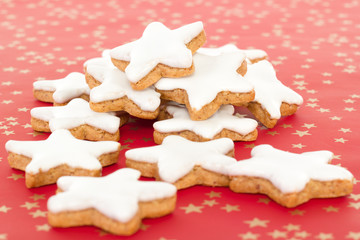 Many star shaped cinnamon biscuits on red background