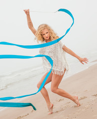 gymnast woman dance with ribbon on the beach