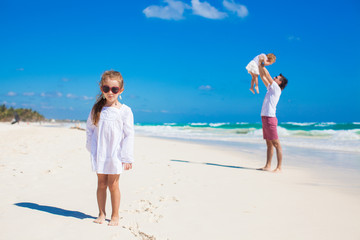 Young father and his cute daughters having fun on white beach