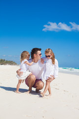 Young happy father and cute daughters having fun on white beach