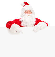 Santa claus posing behind a blank billboard and pointing