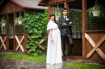 groom and pregnant bride posing against wooden alcove