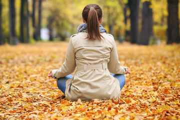 Woman meditating in the park in autumn