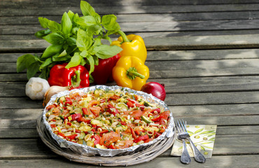 Vegetable tart on rustic wooden table in the garden. Selective f