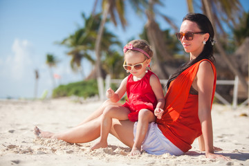 Little girl relaxing on the beach with her young mom