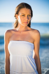 Fototapeta na wymiar Serious brunette in white summer dress posing