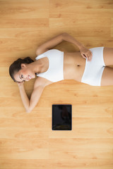Young sporty brunette lying next to a tablet